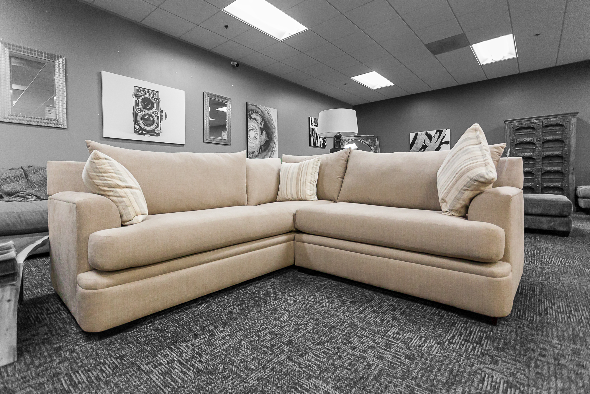 Comfortable L-shaped sectional in light beige with overstuffed pillows and deep seating.