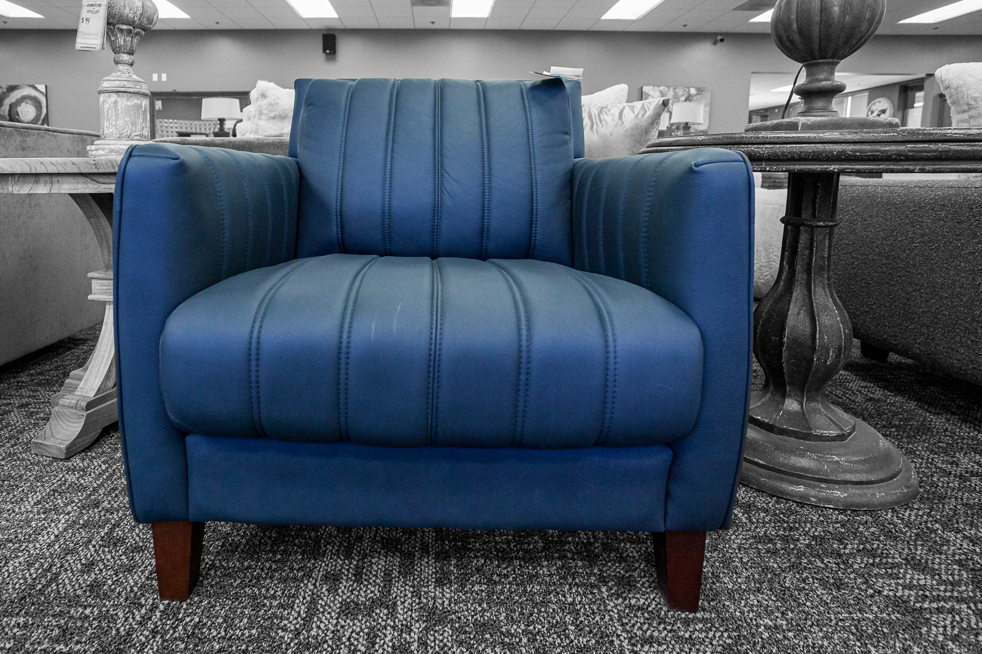 A vibrant blue velvet armchair with channel tufting and tapered wood legs.