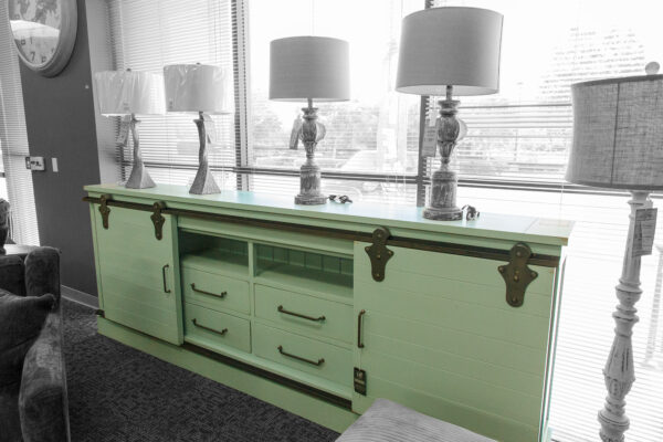 Mint green sliding-door sideboard with black hardware, topped with tall table lamps in front of a large window.