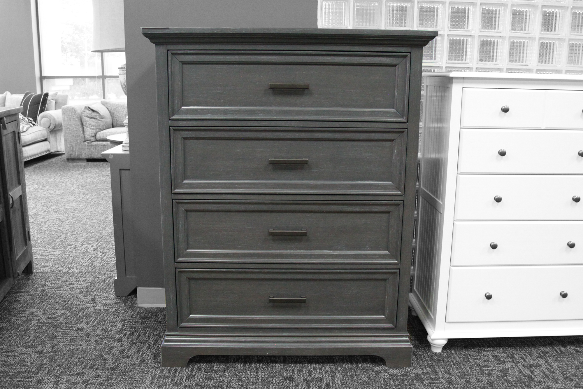 A large heather gray four-drawer chest, with a smaller white 5-drawer dresser next to it.