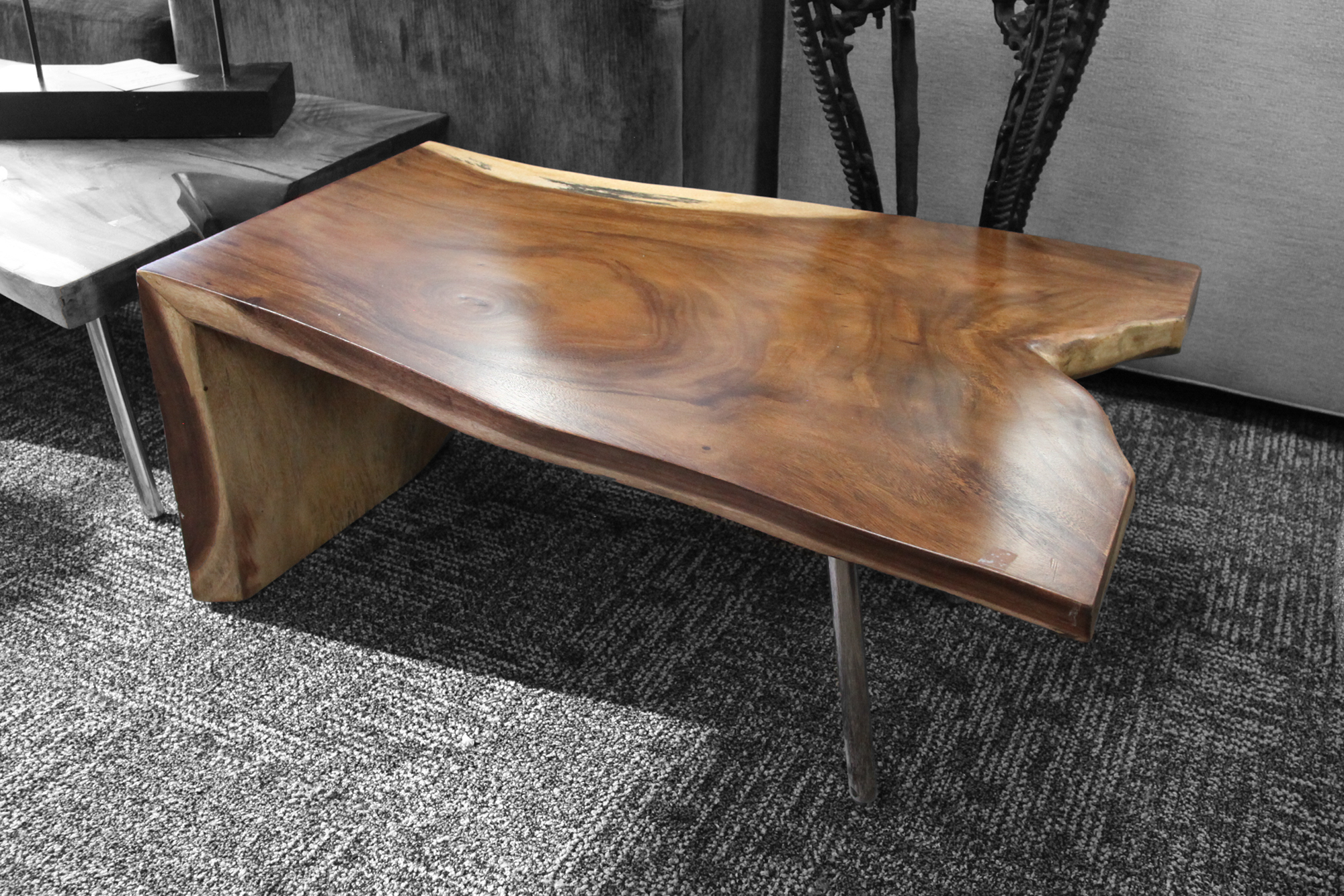 A live edge wood end table with organic shape and rich grain in living room display.