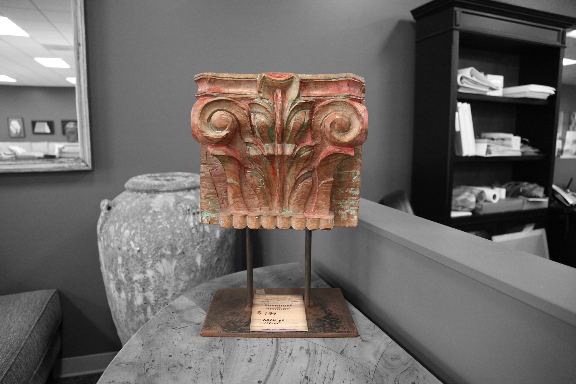 Antique carved wood arch with red accents displayed on metal stand
